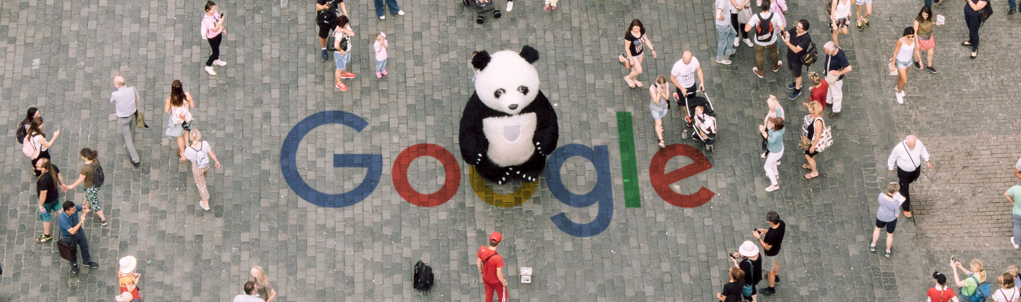 A panda standing in a crowded public space, and the Google logo has been painted on the cobblestones beneath its feet