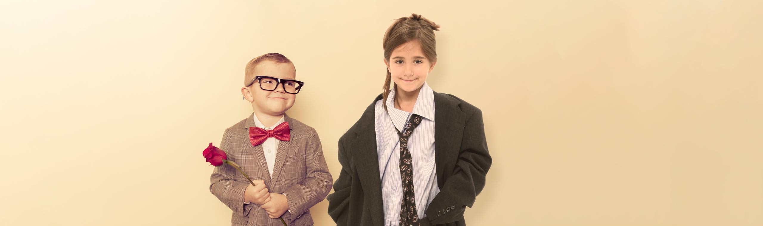 A young boy in a smart suit and a girl in a poorly fitting suit