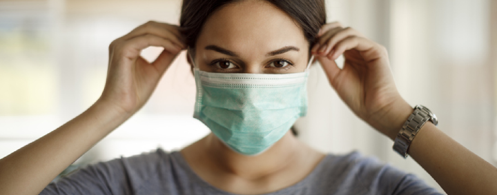 A woman putting on a surgical mask