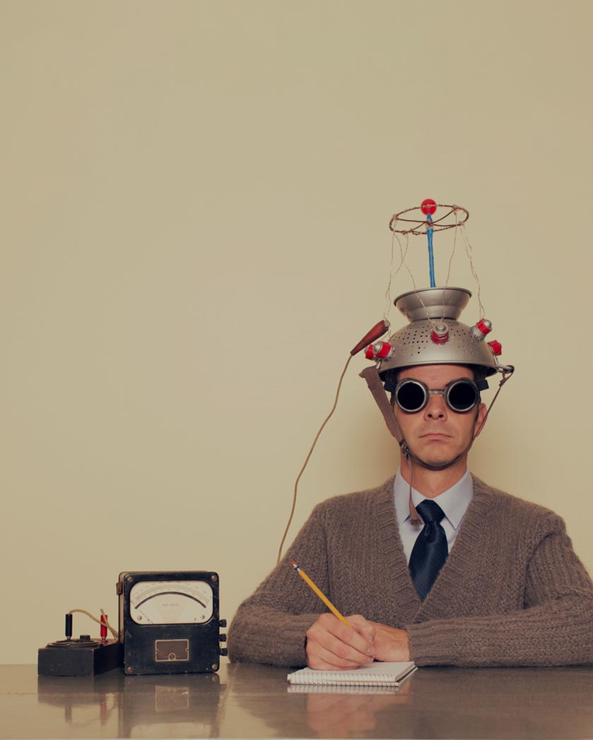 A man at a desk hooked up to abizarre heath-robinson style headpiece