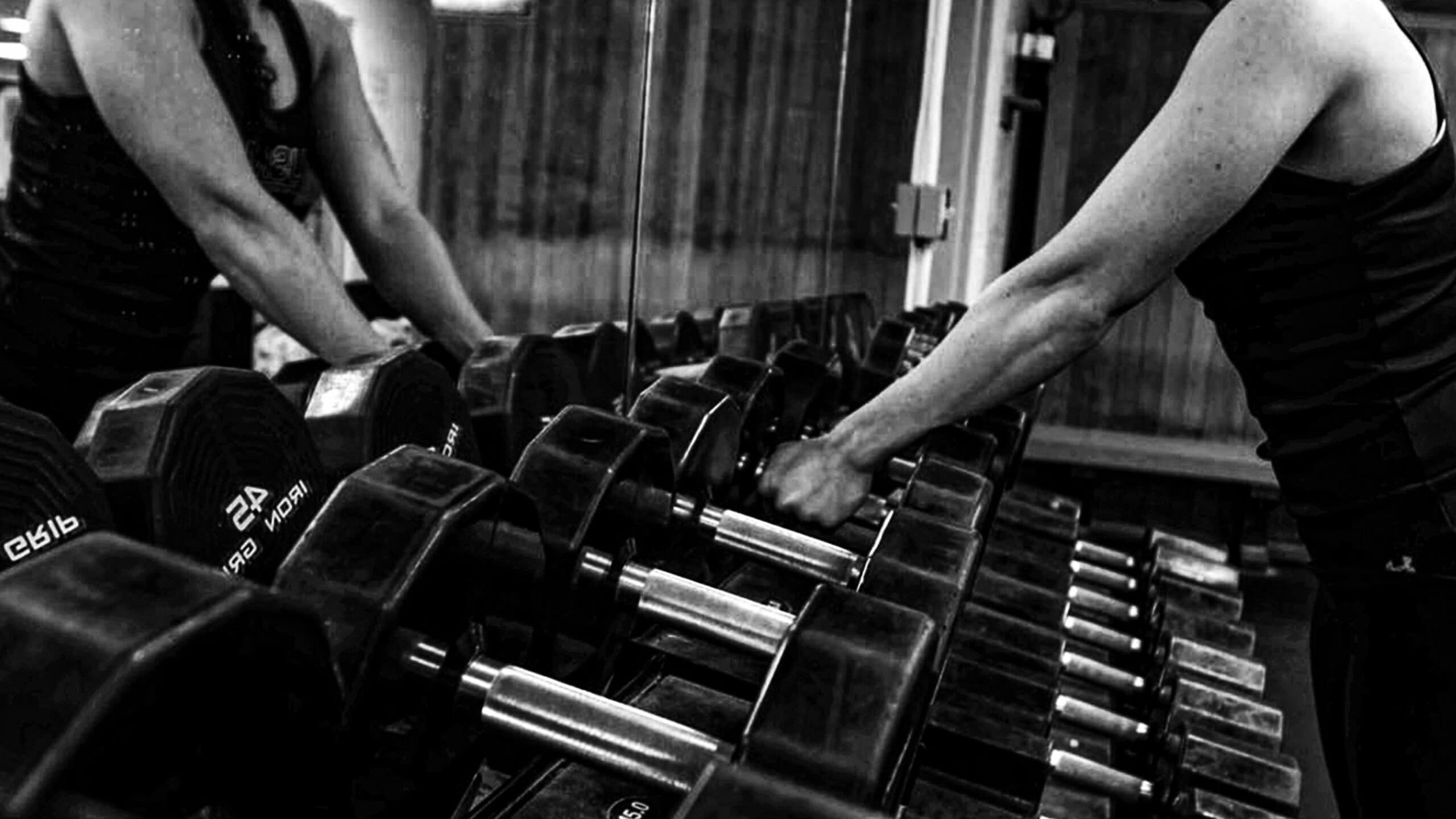 A pair of arms reaching for weights on a rack