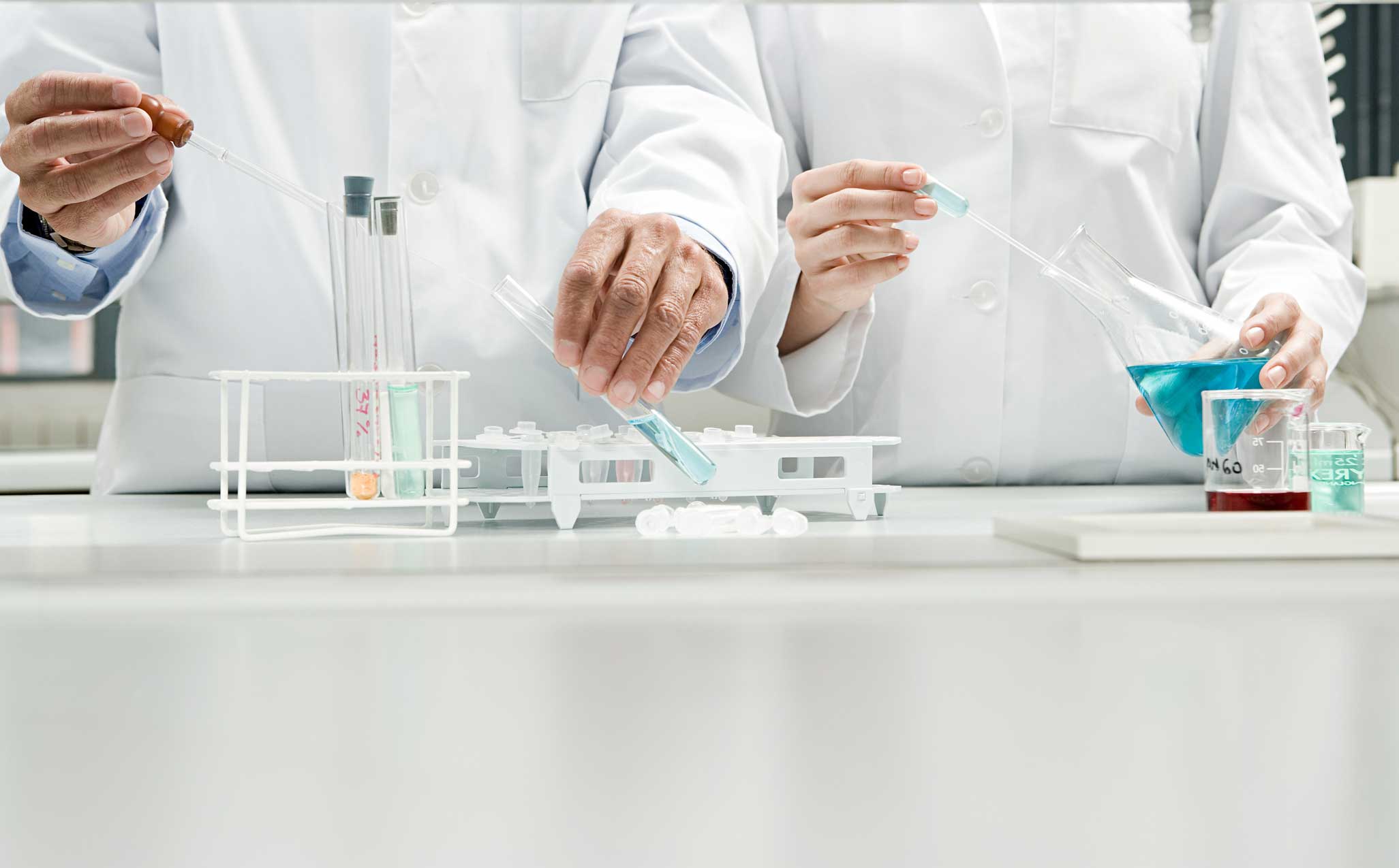 Chemists in white lab coats using lab equipment